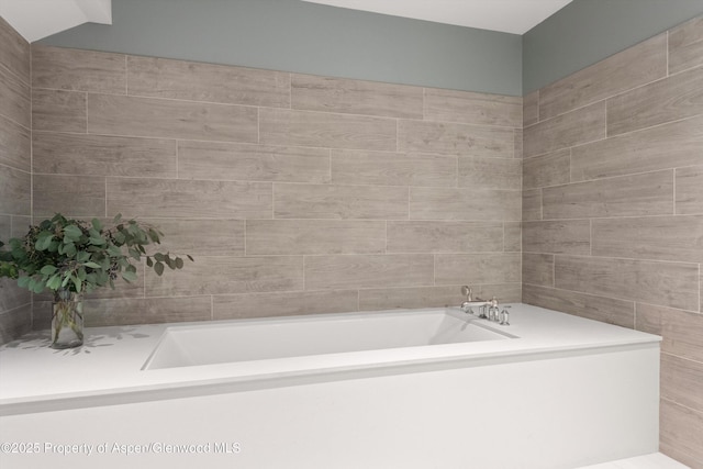 bathroom with tile walls and a bath