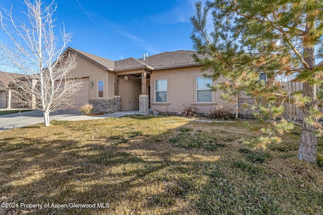 view of front of home featuring a garage, stone siding, fence, and stucco siding