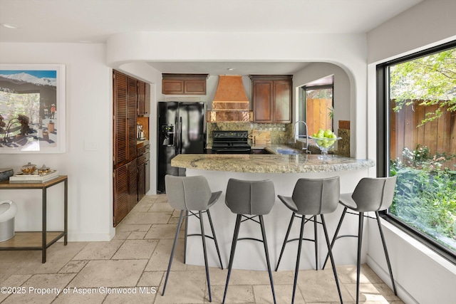 373 Sopris Creek Rd Unit 6, Basalt, CO 81621 - kitchen featuring black appliances, custom range hood, decorative backsplash, a breakfast bar area, and a peninsula
