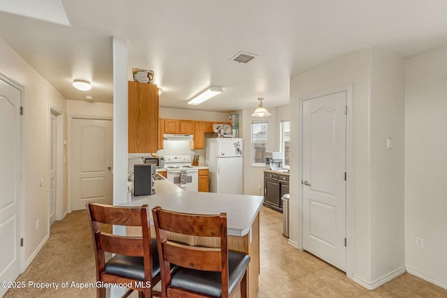 kitchen with under cabinet range hood, a peninsula, white appliances, visible vents, and light countertops