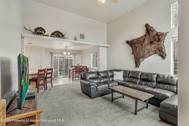 carpeted living room featuring visible vents and ceiling fan with notable chandelier