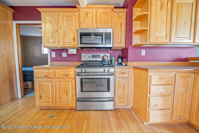 kitchen featuring appliances with stainless steel finishes, light countertops, light wood-style flooring, and open shelves