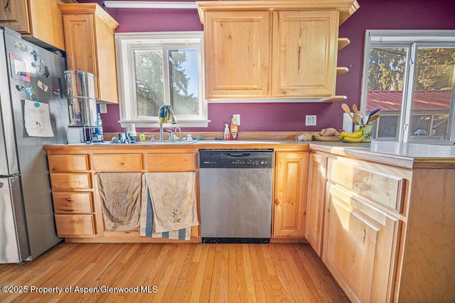 kitchen featuring a sink, light countertops, appliances with stainless steel finishes, light wood-type flooring, and light brown cabinetry