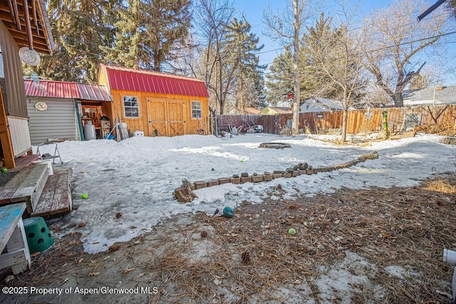 yard covered in snow with an outbuilding and fence