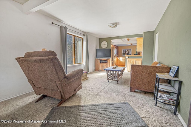 living area featuring light carpet, beamed ceiling, and baseboards