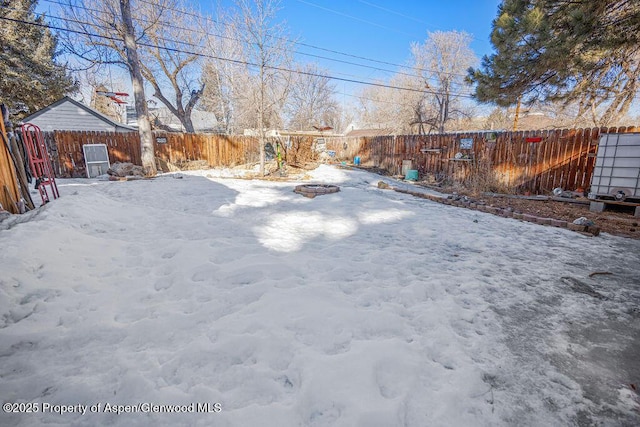 yard layered in snow with an outdoor fire pit and a fenced backyard