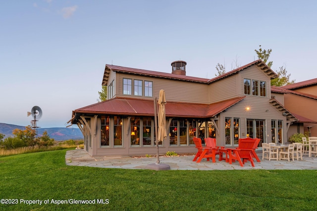 rear view of property with a mountain view, a patio area, and a yard