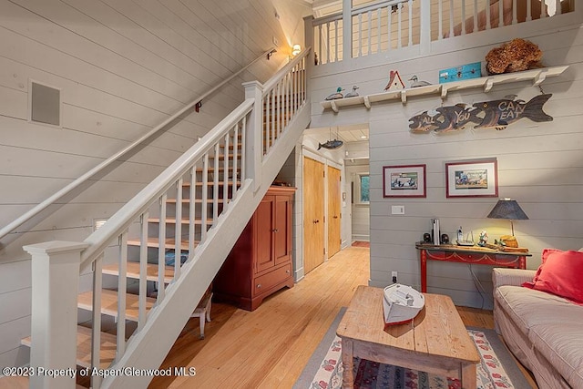 staircase featuring hardwood / wood-style floors, a towering ceiling, and wooden walls