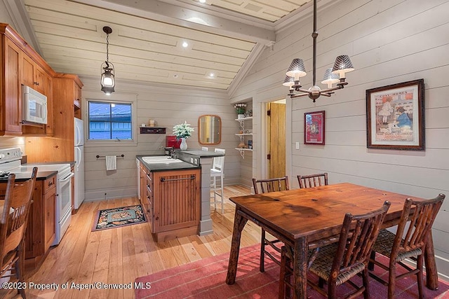 kitchen with white appliances, lofted ceiling with beams, light wood-type flooring, decorative light fixtures, and stainless steel counters