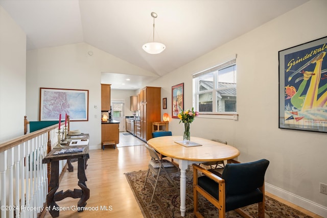 dining room with light wood-type flooring and vaulted ceiling