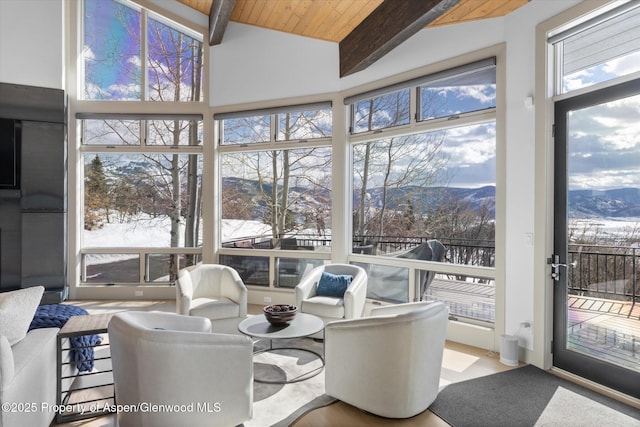 sunroom with vaulted ceiling with beams, wooden ceiling, and a mountain view