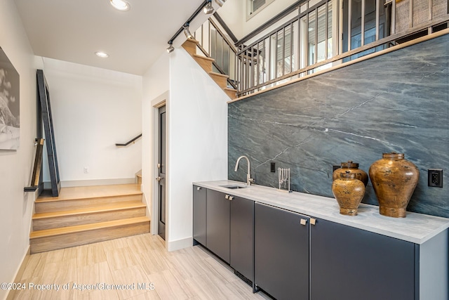 bar featuring recessed lighting, backsplash, a sink, baseboards, and stairs