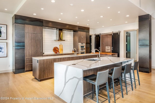 kitchen featuring a spacious island, a barn door, modern cabinets, and a sink