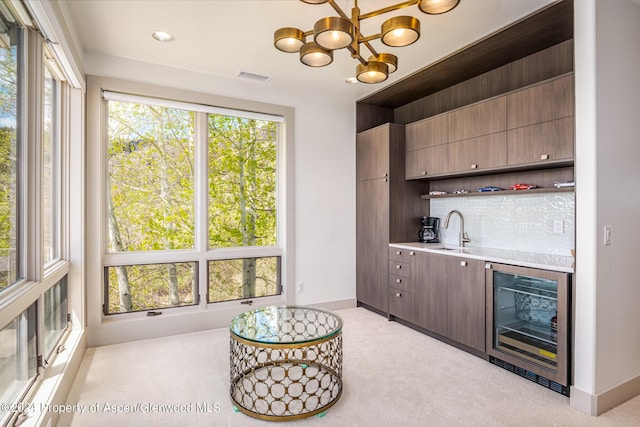 bar with a wealth of natural light, beverage cooler, a sink, and backsplash