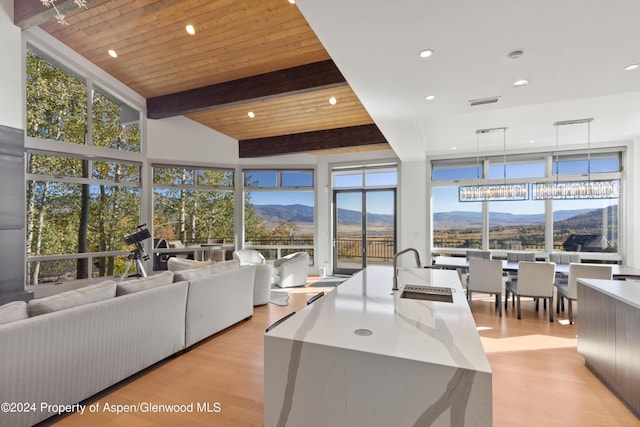 living room with light wood-type flooring, wood ceiling, a mountain view, and beamed ceiling