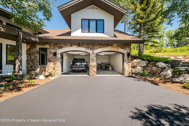 view of front of property with aphalt driveway, stone siding, a garage, and stucco siding