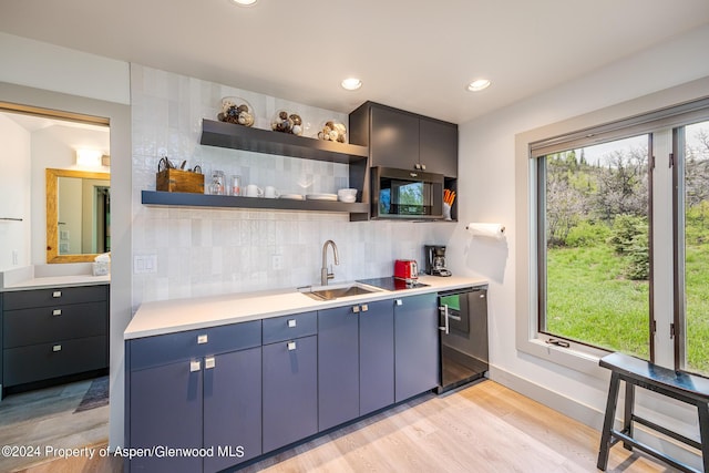 kitchen with open shelves, stainless steel microwave, backsplash, a sink, and dishwasher