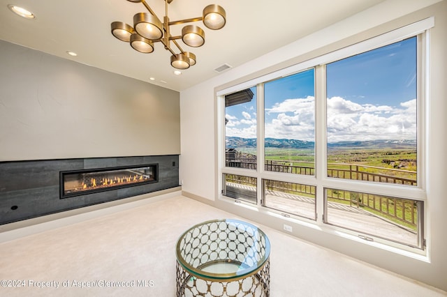 living area with carpet floors, a notable chandelier, recessed lighting, visible vents, and a glass covered fireplace