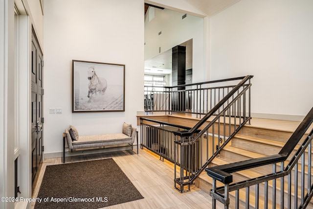 staircase with a high ceiling, wood finished floors, and baseboards