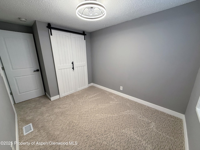 455 E 7th St, Craig, CO 81625 - unfurnished bedroom featuring a barn door, a textured ceiling, carpet flooring, baseboards, and a closet