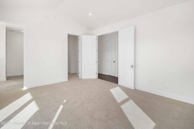 unfurnished bedroom with light colored carpet and lofted ceiling