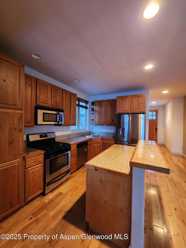 kitchen featuring light hardwood / wood-style floors, stainless steel appliances, a kitchen island, a wealth of natural light, and sink