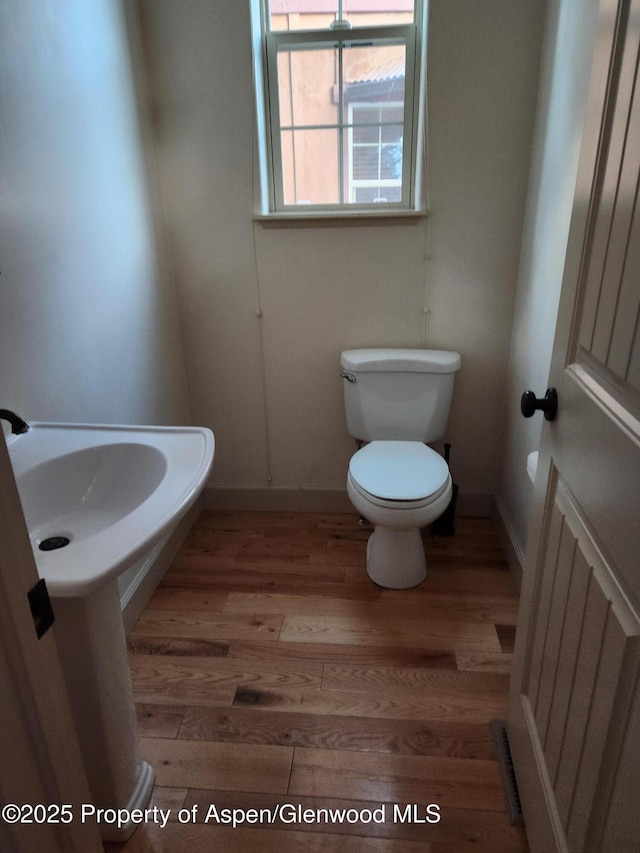 bathroom featuring toilet, hardwood / wood-style floors, and radiator heating unit