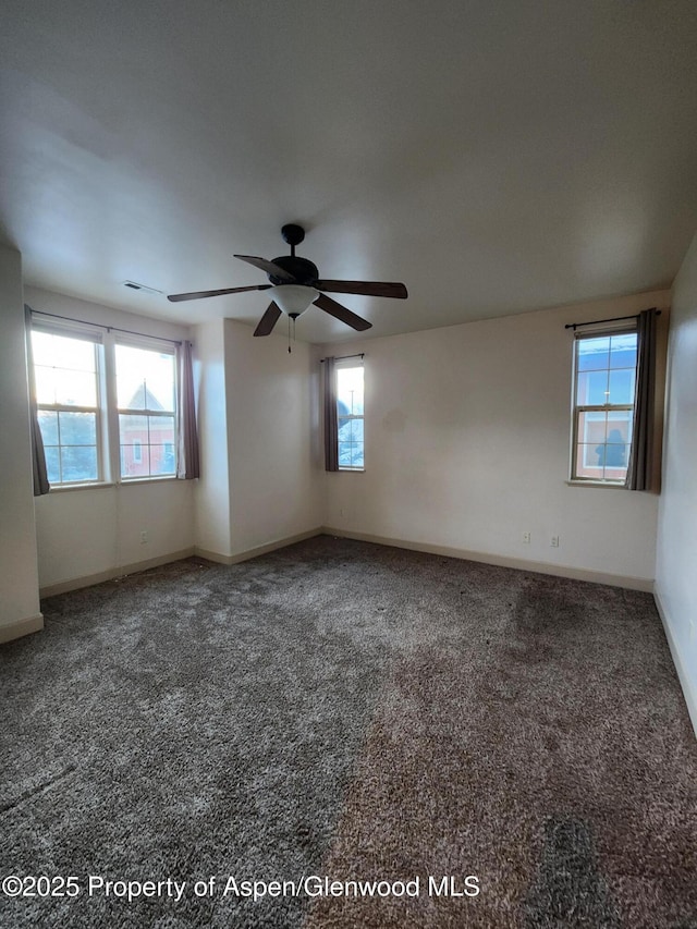 spare room featuring ceiling fan, a wealth of natural light, and carpet