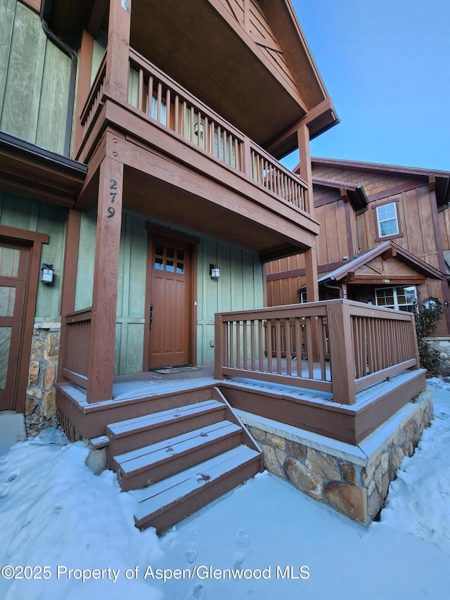 snow covered property entrance featuring a balcony