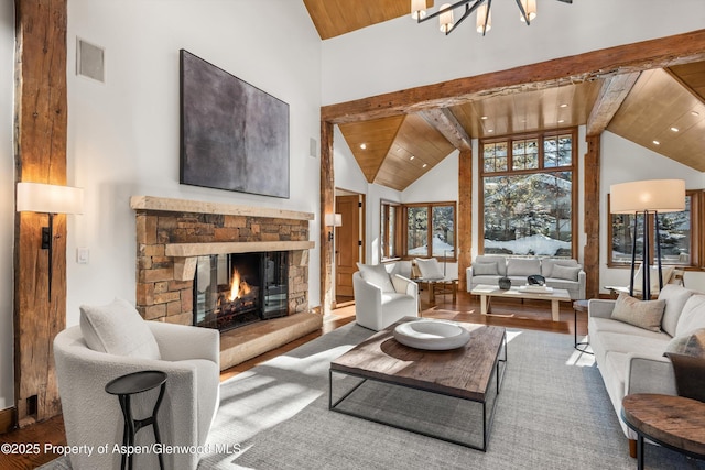 living room with wood-type flooring, wooden ceiling, beamed ceiling, a chandelier, and a stone fireplace