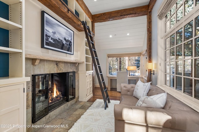 living room featuring beam ceiling and a tiled fireplace