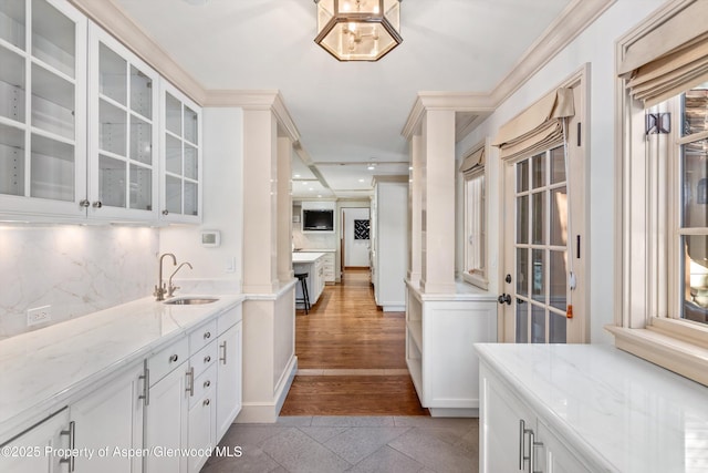 kitchen with white cabinets, decorative backsplash, light stone counters, and sink