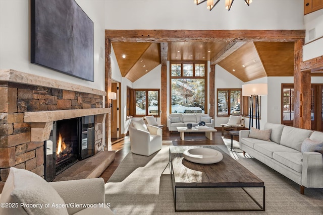 living room featuring a stone fireplace, beamed ceiling, wooden ceiling, and high vaulted ceiling