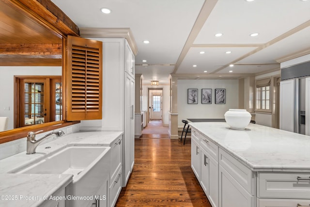 kitchen with light stone countertops, white cabinets, dark wood-type flooring, and sink