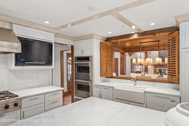 kitchen featuring sink, wall chimney range hood, tasteful backsplash, pendant lighting, and appliances with stainless steel finishes