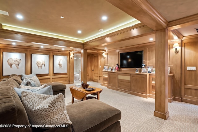 carpeted home theater featuring beam ceiling, wood walls, and crown molding