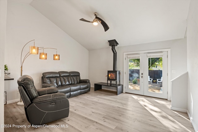 living room with a wood stove, ceiling fan, french doors, light hardwood / wood-style flooring, and high vaulted ceiling