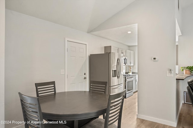 dining space featuring light hardwood / wood-style floors and vaulted ceiling