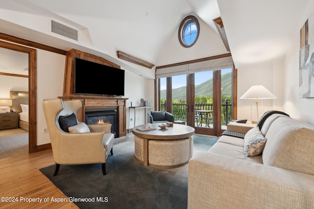 living room featuring light wood-type flooring, french doors, and vaulted ceiling