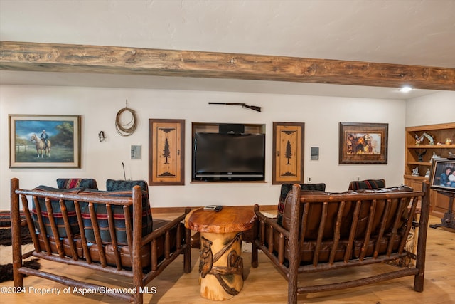 living room featuring beamed ceiling and light hardwood / wood-style floors