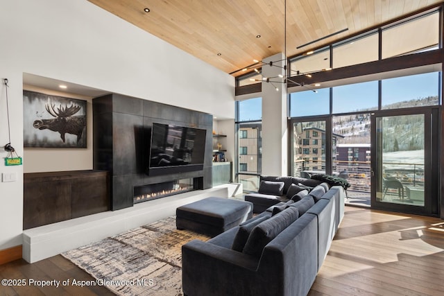 living room featuring wood ceiling, a large fireplace, light hardwood / wood-style flooring, and a high ceiling