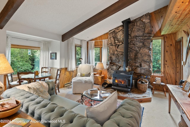 living room with lofted ceiling with beams, wood walls, a wood stove, and a baseboard heating unit