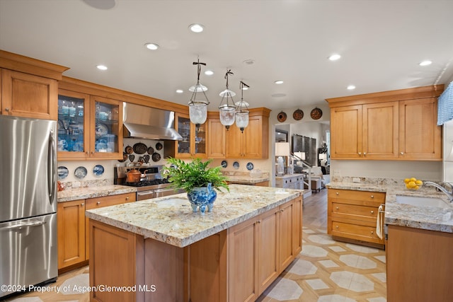 kitchen featuring a center island, sink, wall chimney exhaust hood, light stone countertops, and appliances with stainless steel finishes