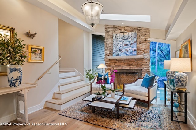 living room with a fireplace, wood-type flooring, and vaulted ceiling with skylight