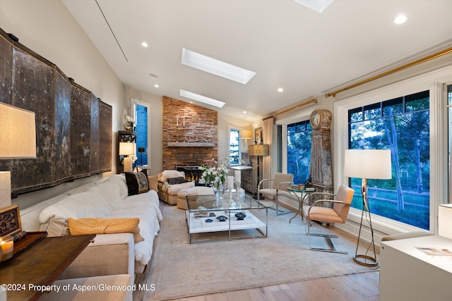 living room featuring a fireplace, light wood-type flooring, and lofted ceiling with skylight