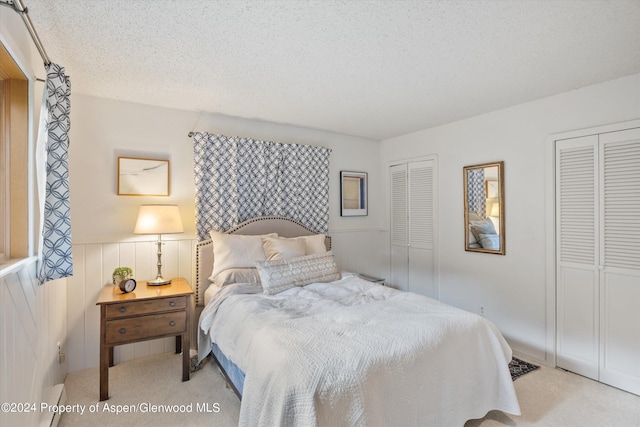 carpeted bedroom featuring multiple closets and a textured ceiling