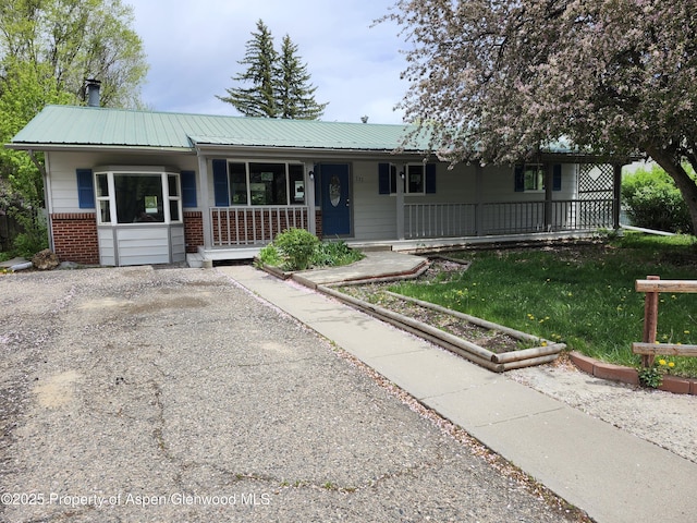 737 Rose St, Craig, CO 81625 - single story home with covered porch, brick siding, metal roof, and a front lawn