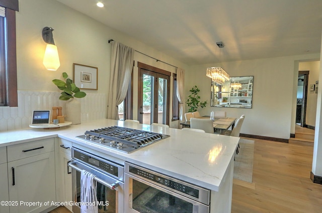 86 Sunrise Ct, Glenwood Springs, CO 81601 - kitchen featuring appliances with stainless steel finishes, a chandelier, light wood-type flooring, a peninsula, and backsplash