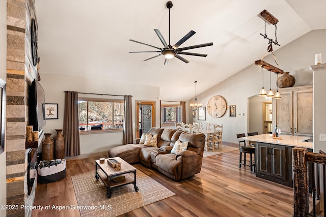 living room featuring lofted ceiling, ceiling fan with notable chandelier, and hardwood / wood-style floors