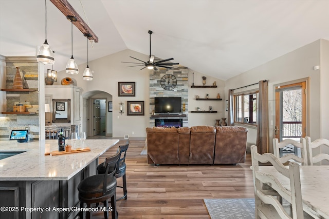 living room featuring ceiling fan, a fireplace, vaulted ceiling, light hardwood / wood-style flooring, and sink